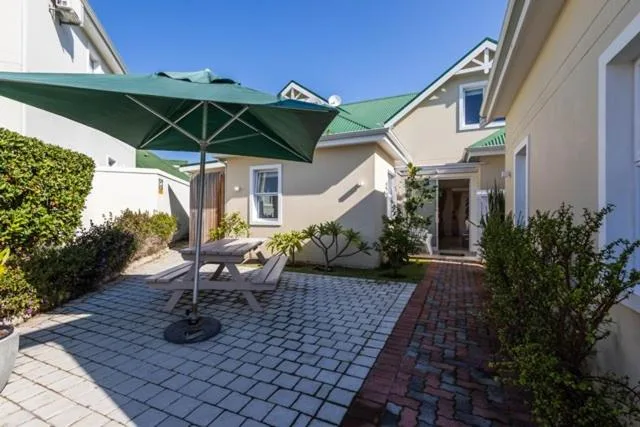 Paved courtyard with large green umbrella and outdoor seating area