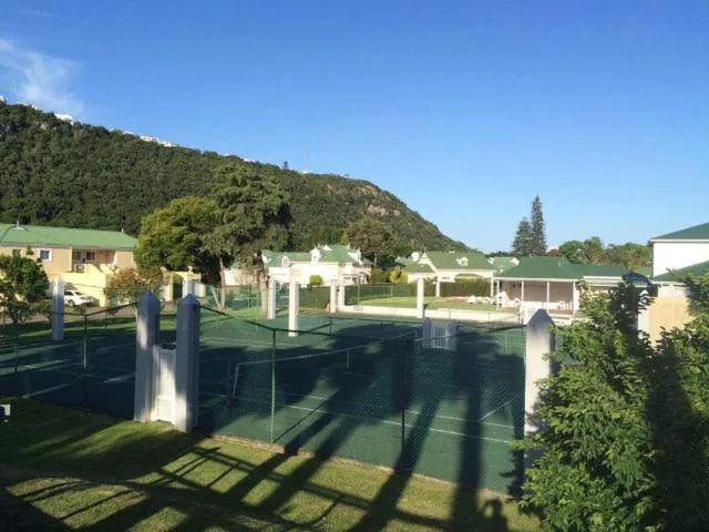 Garden Route property with manicured lawns, white pergolas, and forested hillside backdrop