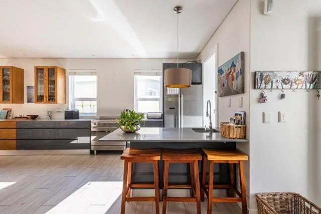 Modern kitchen with black countertops, wooden bar stools, and stainless steel appliances