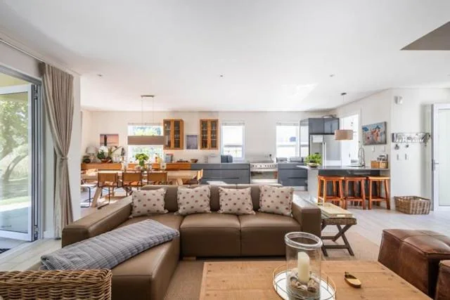 Open-plan living room with brown sectional sofa and kitchen visible beyond