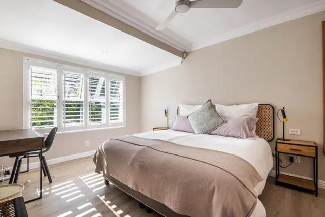 Bright bedroom with queen bed, shuttered windows, and wooden desk area