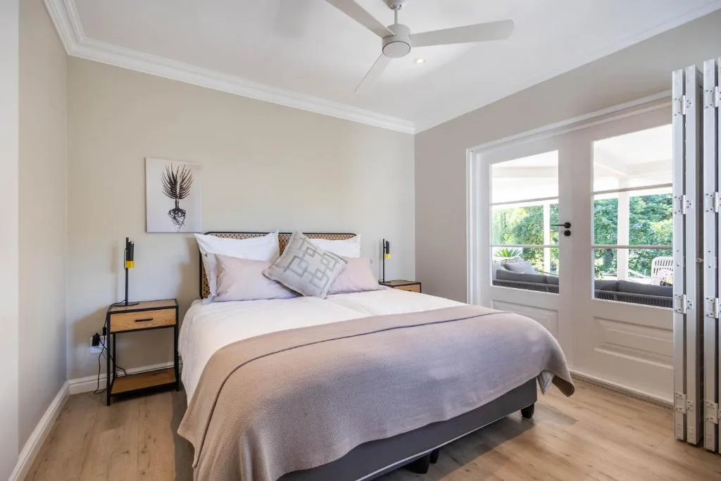 Bright bedroom with queen bed, modern nightstands, and glass doors opening onto deck