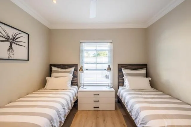 Twin bedroom with two single beds, neutral bedding, and bright window