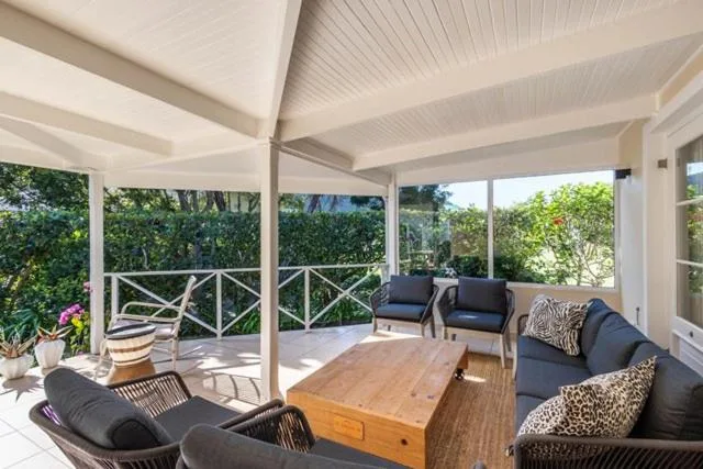 Covered outdoor seating area with comfortable loungers and garden views