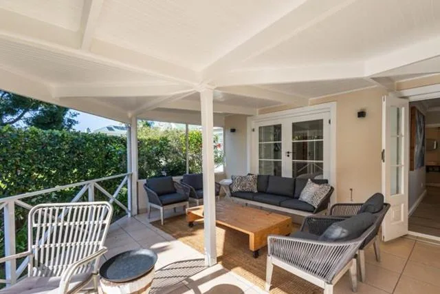 Covered outdoor patio with seating, white railings, and garden views