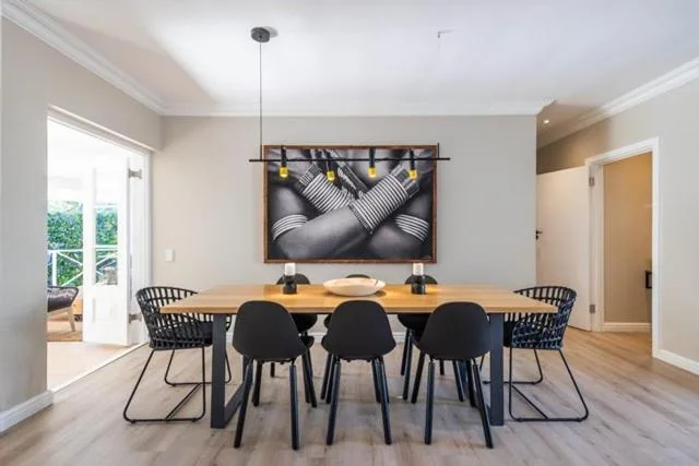 Modern dining room with wooden table and black chairs under contemporary artwork