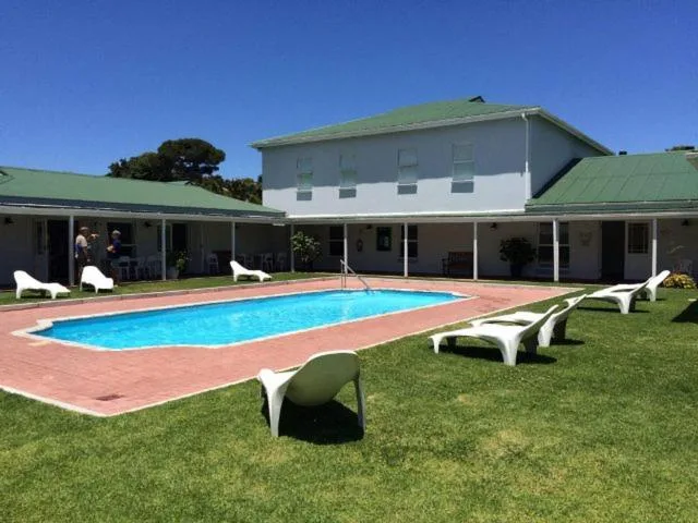Rectangular swimming pool with lounge chairs on manicured lawn