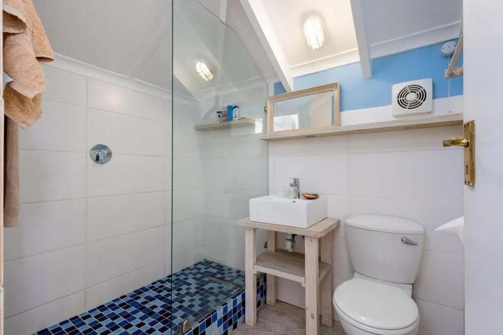 Modern bathroom with walk-in shower, white vanity, and blue tile accents