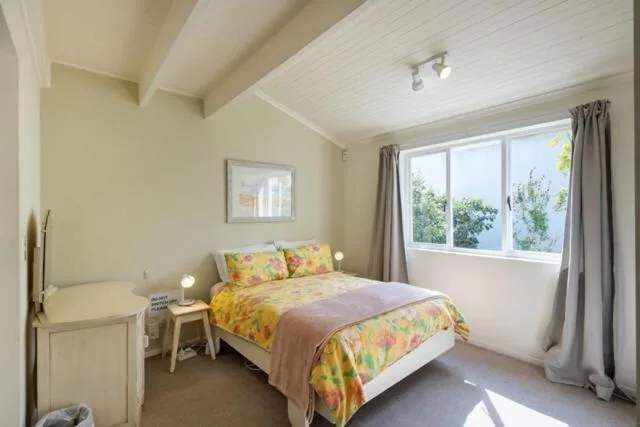 Bright bedroom with colorful bedding, large window, and natural light