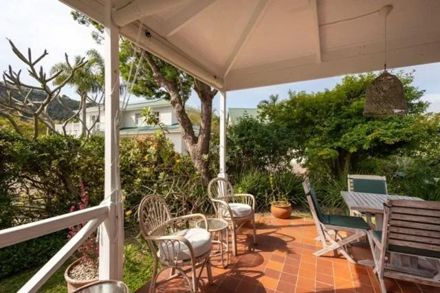 Covered patio with wicker chairs and lush garden surroundings