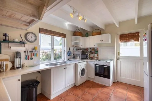 Bright kitchen with white cabinetry, terracotta floor, and garden views