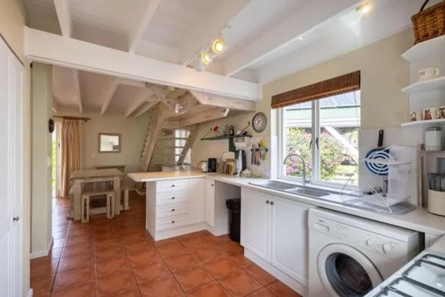 Bright kitchen with white cabinetry, washing machine, and terracotta tiles