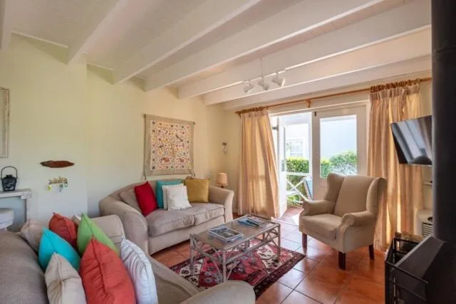 Bright living room with comfortable seating and colorful cushions overlooking garden