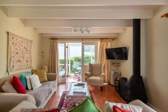 Bright living room with sofa, armchairs, and sliding doors to deck