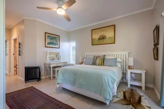 Bright bedroom with white bed, ceiling fan, and nautical artwork on walls