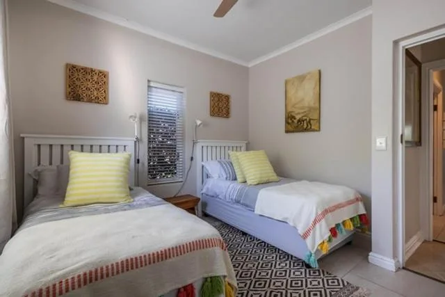 Twin bedroom with yellow cushions, woven wall art, and natural light