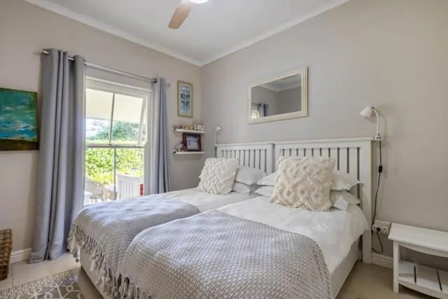 Bright bedroom with white wooden bed frame and garden view windows