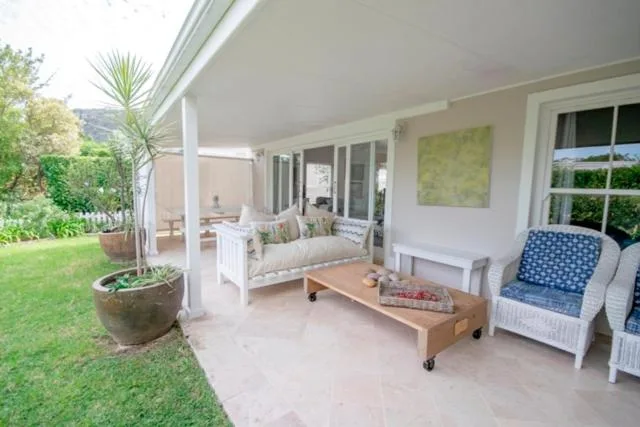 Covered patio with seating, wicker chairs, and garden views