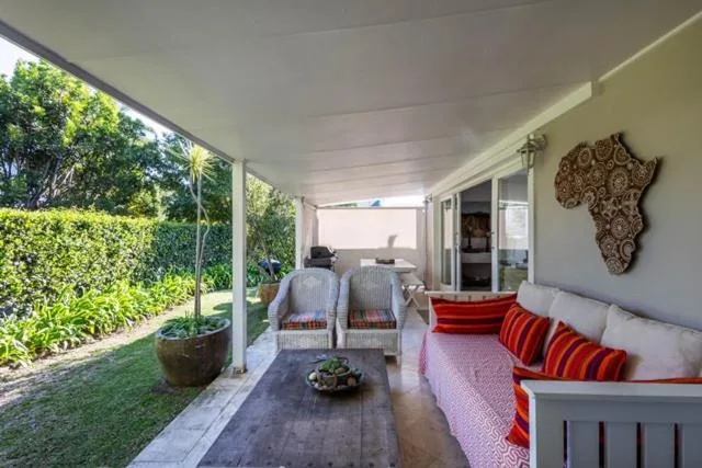 Covered patio with seating, garden views, and African wall decor