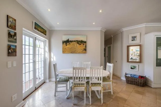 Bright dining area with white chairs and table near glass doors