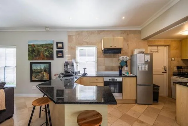 Open-plan kitchen with stainless steel appliances and black granite countertop