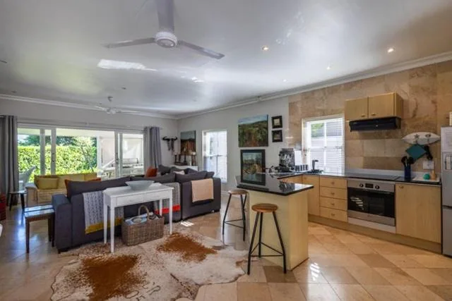 Open-plan living area with dark sofa, kitchen island, and garden views