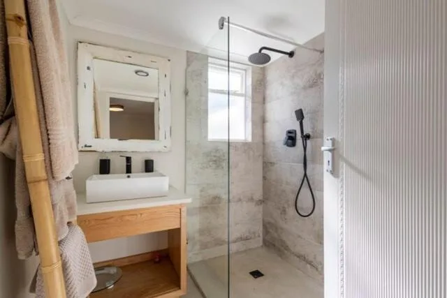 Modern bathroom with vanity sink, mirror, and walk-in shower enclosure