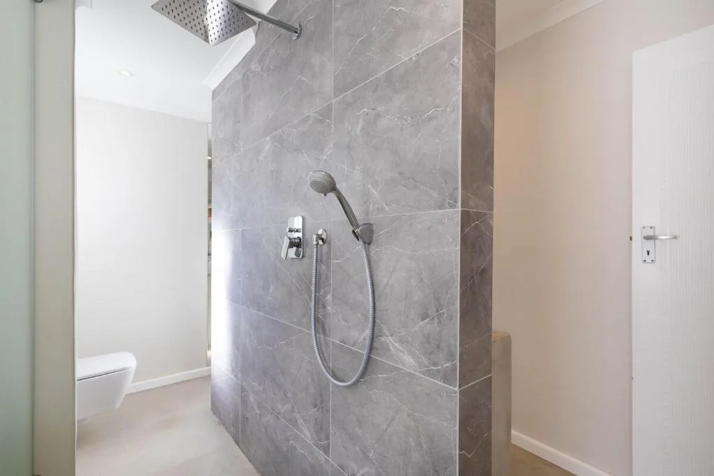 Modern bathroom with gray marble shower enclosure and rainfall showerhead