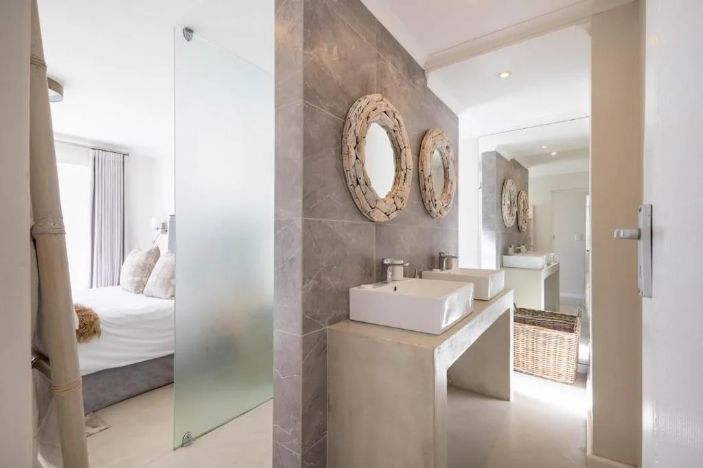Modern bathroom with vessel sink, gray tile walls, and coastal decor mirrors