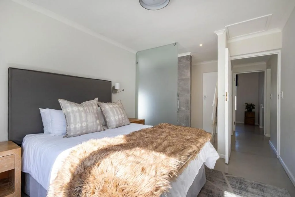 Modern bedroom with queen bed, gray headboard, and en-suite bathroom access