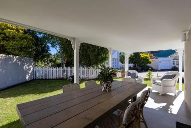 Covered outdoor dining area with table overlooking manicured garden and lawn