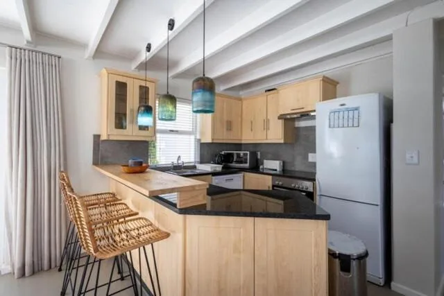Modern kitchen with light wood cabinetry, black countertops, and pendant lighting