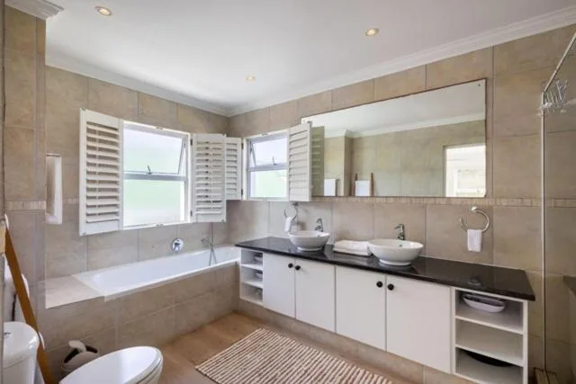 Modern bathroom with dual vanity, bathtub, and large mirror