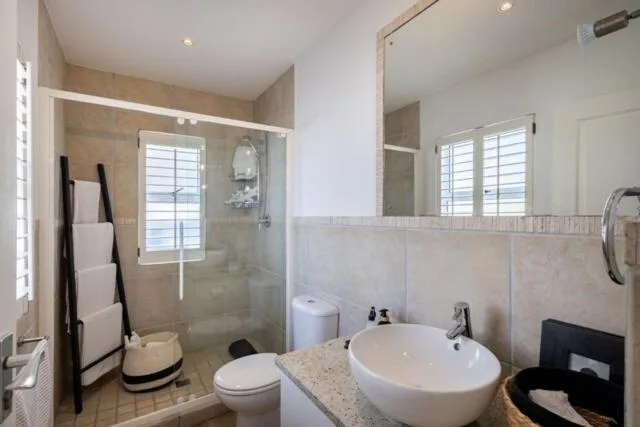 Modern bathroom with walk-in shower, dual vanity sinks, and toilet fixtures