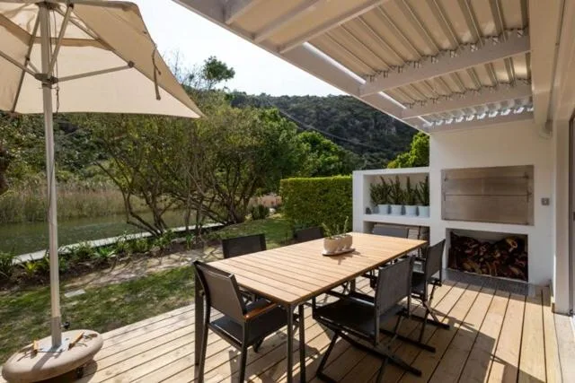 Covered wooden deck with dining table and umbrella, garden views