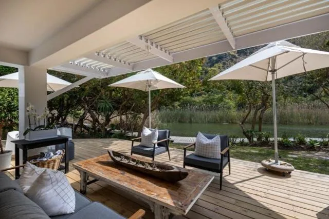 Spacious wooden deck with pergola, umbrellas, seating, and river views