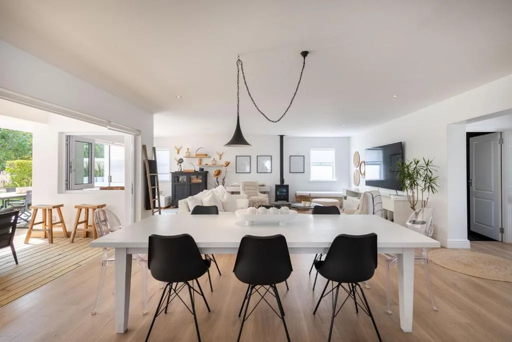 Open-plan dining area with white table and black chairs overlooking lounge