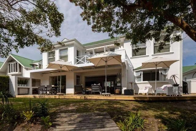 Modern white holiday home with green roof and shaded deck area