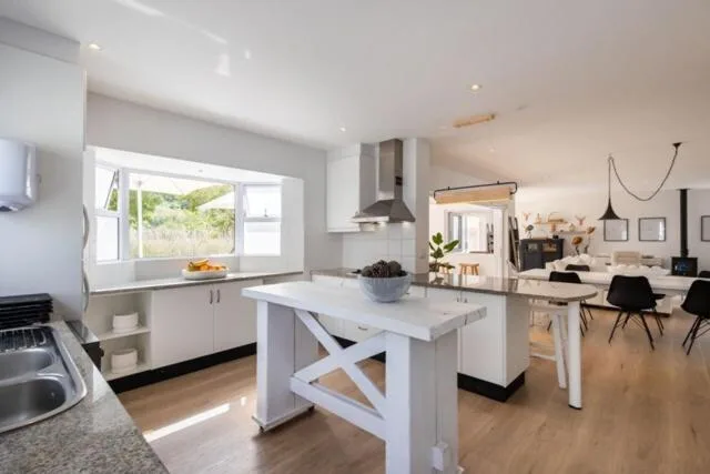 Modern open-plan kitchen with white cabinetry, island bench, and garden views