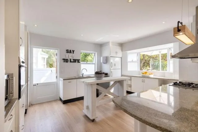 Modern kitchen with white cabinetry, island counter, and garden views