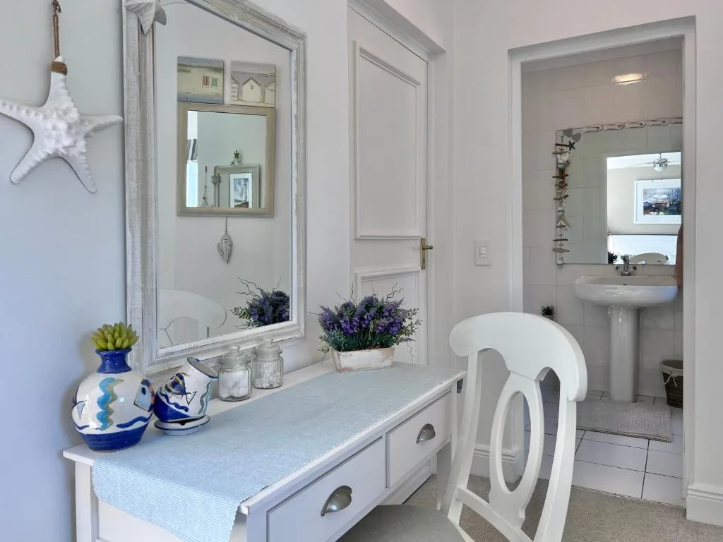 Bright bathroom with vanity, mirror, pedestal sink, and coastal decor touches