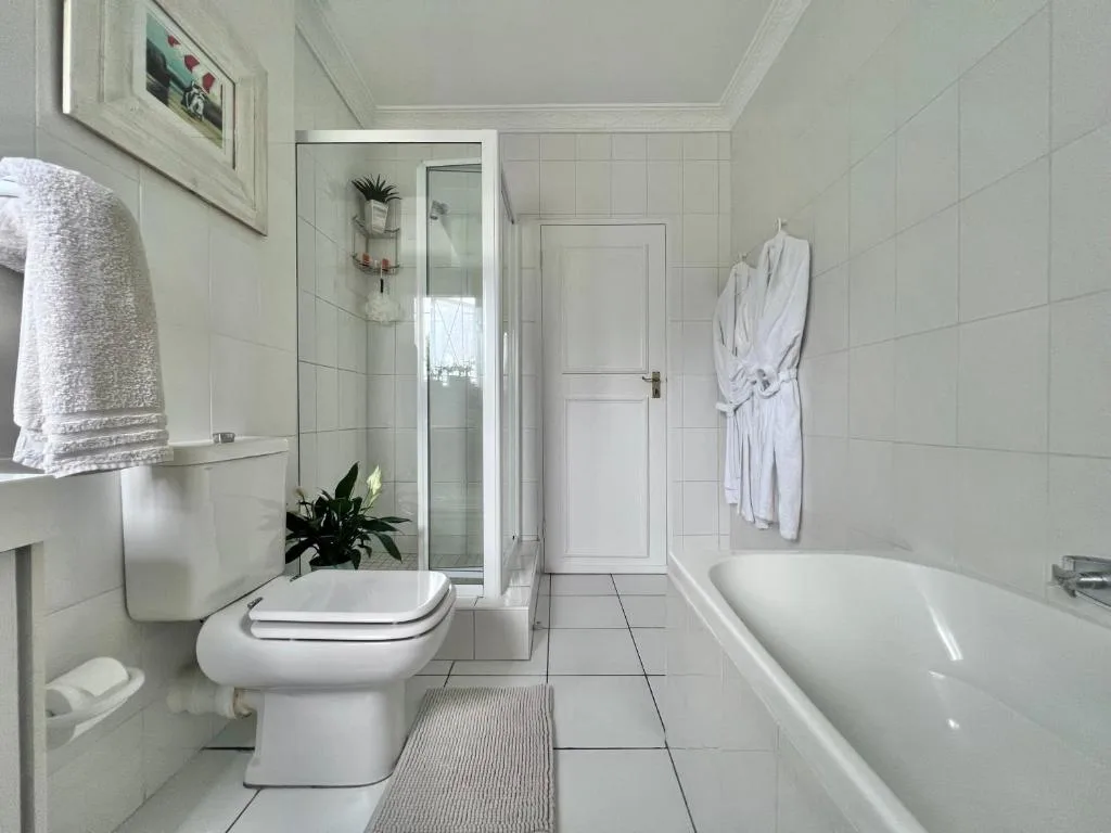 Clean white bathroom with bathtub, toilet, shower enclosure and towels