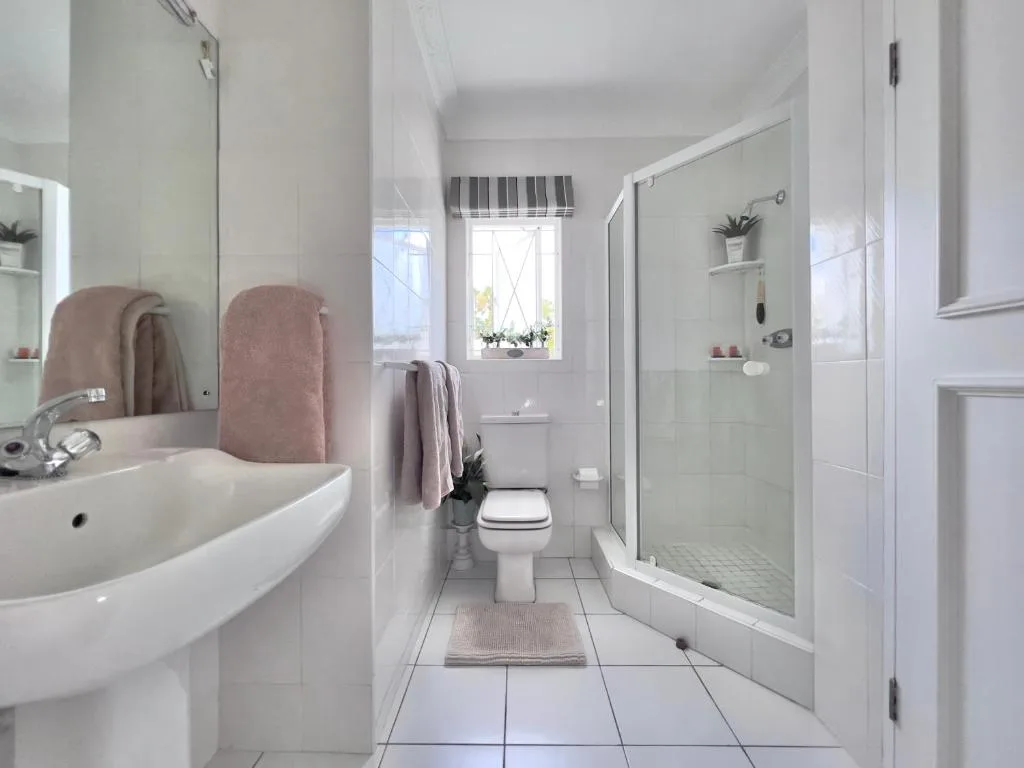 Clean bright bathroom with vanity, toilet, and walk-in shower enclosure
