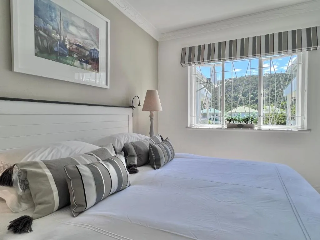 Bright bedroom with white headboard, striped pillows, mountain view through window