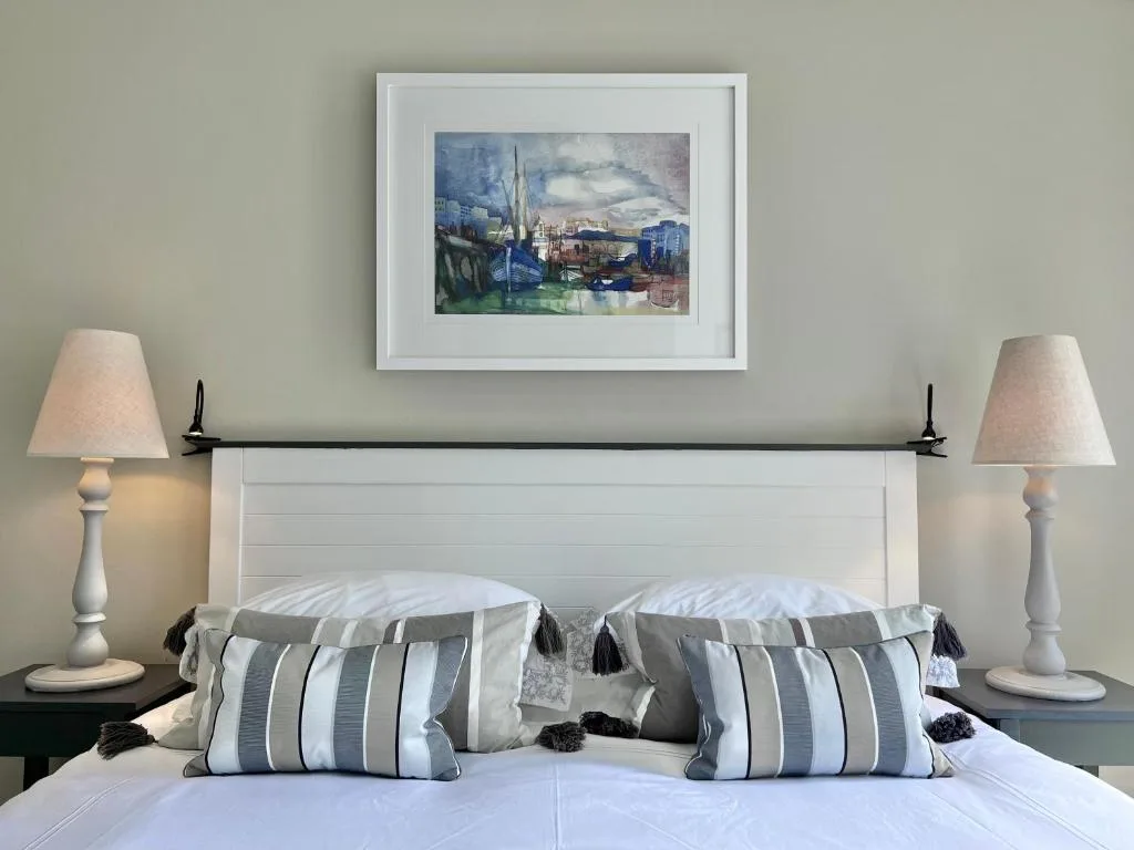 Bedroom with white headboard, striped pillows, and bedside lamps
