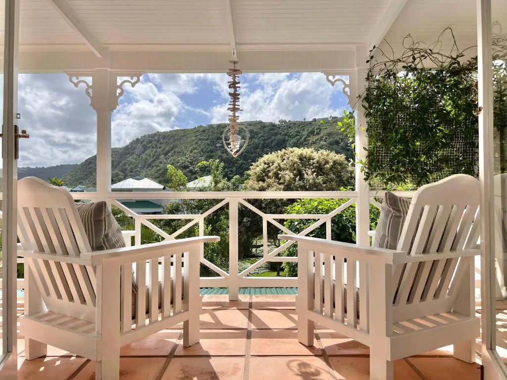 Covered deck with white chairs overlooking forested hills and valley