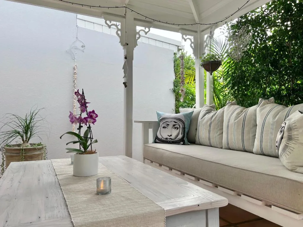 Covered patio with comfortable seating, potted orchid, and lush green surroundings
