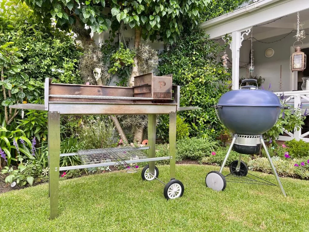 Garden braai area with spherical grill and vintage barbecue on manicured lawn