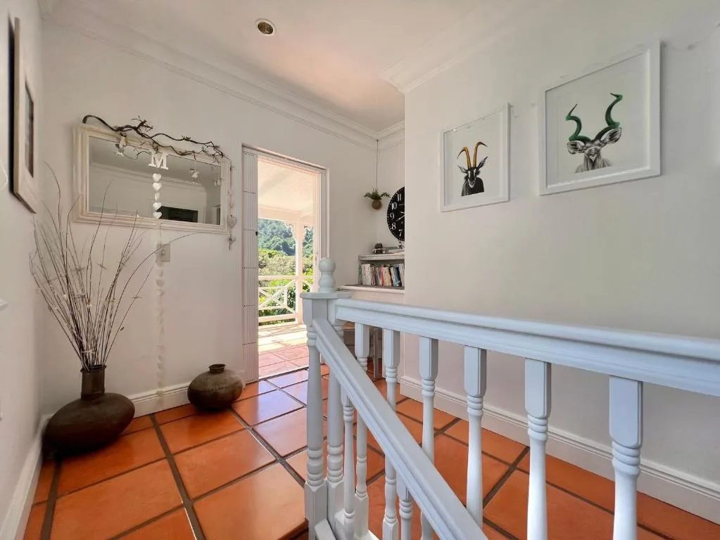 Hallway with white railing, terracotta tiles, and artwork decor