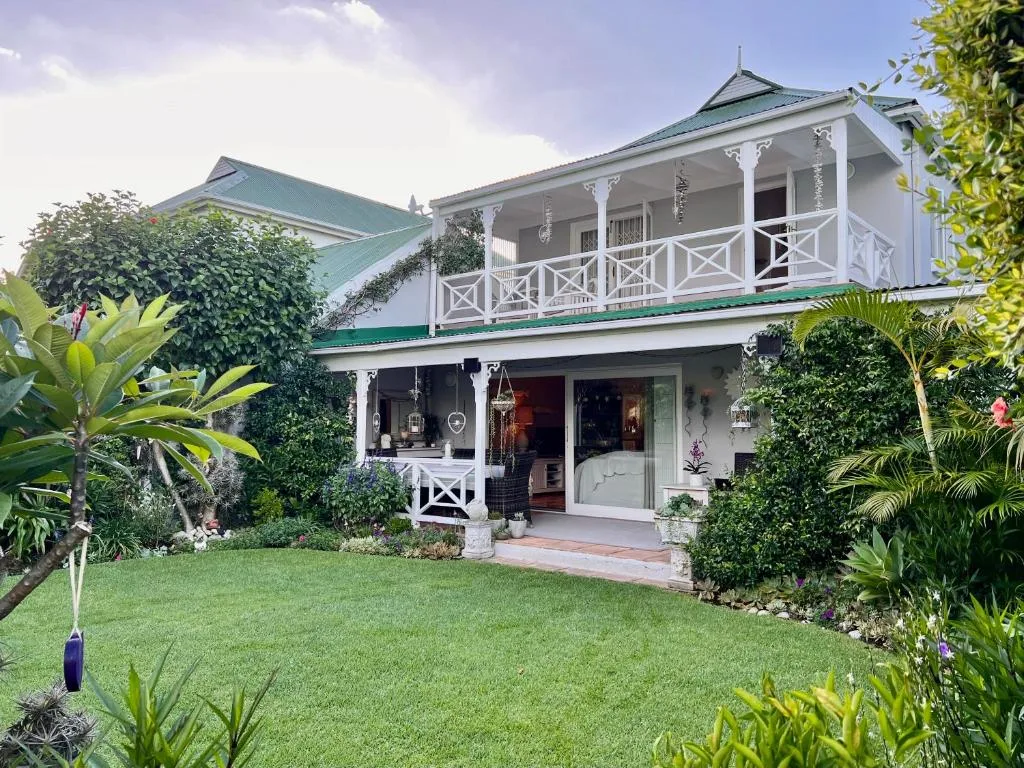 White Victorian-style holiday home with green roof and manicured garden lawn